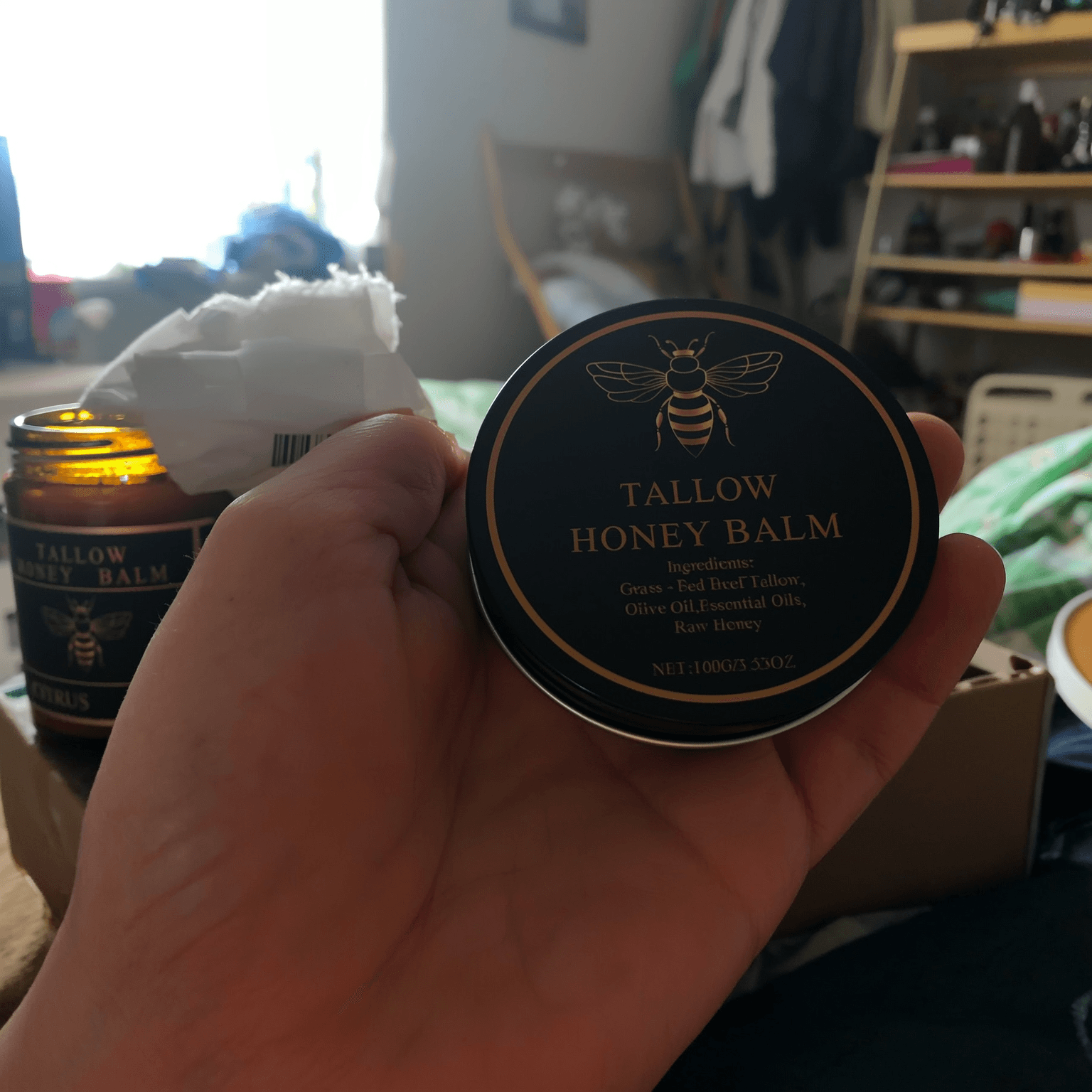 Jar of tallow and honey balm held in an open hand to show its size